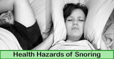 Health Hazards of Snoring. Picture of a caucasian male and female sleeping in bed, with the female having the pillow pulled up around her ears.