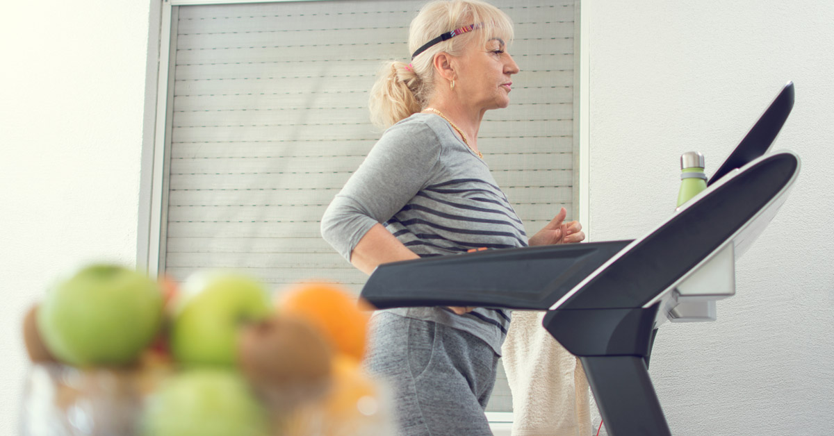 Elderly lady walking on the treadmill in her home.